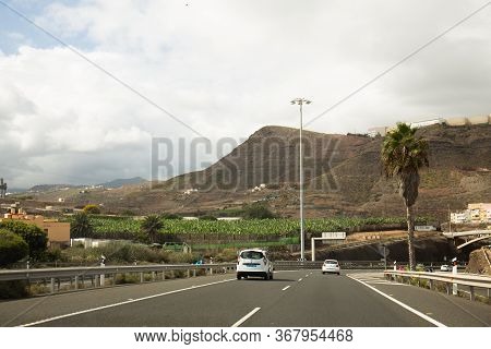Agaete, Las Palmas - October 17, 2019: Vehicles On Road Near Volcano And Palm Trees In Agaete, Las P