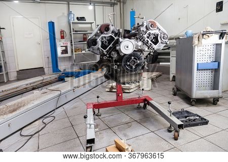 Closeup Of A Eight Cylinder Auto Engine On A Special Red Stand In A Car Workshop. Disassembled Part 