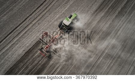 Aerial View Of A Clean Field In Which The Tractor Makes Vertical Tillage. Red Tillage Equipment And 