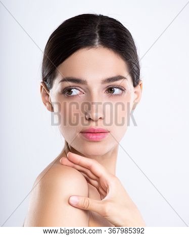 Portrait of beautiful young brunette woman with clean face. Beautiful face of young adult woman with clean fresh skin - isolated on white. Front portrait of woman with beauty face. Beauty concept 