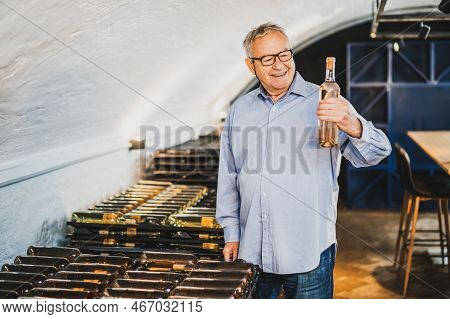 Portrait Of Senior Man Who Owns Winery. He Is Examining Quality In His Wine Cellar. Industry Wine Ma