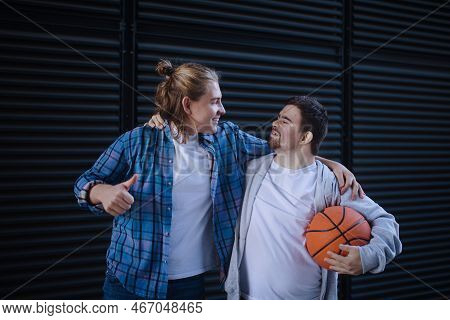 Man With Down Syndrome Playing Basketball Outdoor With His Friend. Concept Of Friendship And Integra