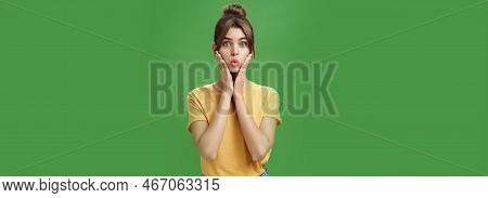 Silly Cute And Tender Young Female Model With Cleacn Skin Folding Lips, Pressing Hands To Cheeks And