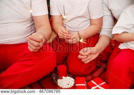 Happy Family Enjoying Xmas. Smiling Family Holding Gift Boxes And Sparkles. Happy Family Celebrating