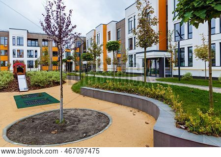Green Recreation Area With Various Shrubs And Trees, A Children\'s Playground In The Yard Of A Multi