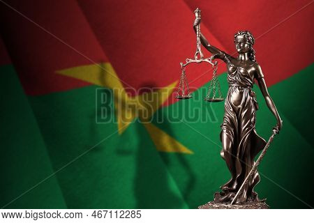 Burkina Faso Flag With Statue Of Lady Justice And Judicial Scales In Dark Room. Concept Of Judgement