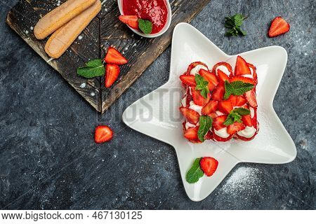 Italian Dessert Tiramisu Cake With Fresh Strawberry, Biscuit And Whipped Cream And Mint On A Dark Ba