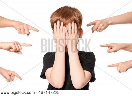 Boy Covering Face With Hands And Kids Pointing At Him On White Background. Children's Bullying