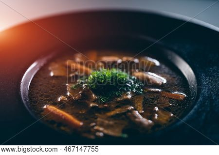Black Plate With Brown Soup Pottage With Mushroom, Carrot, Vegetables, Dill