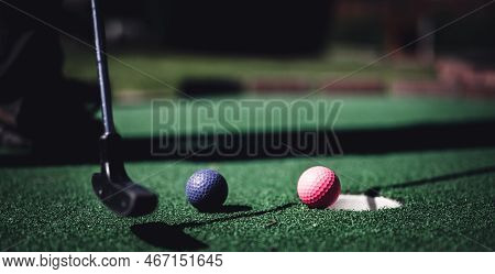 Mini Golf Game With Several Colored Balls In The Way Of A Putter Lined Up.