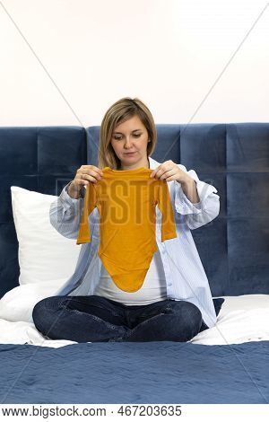 Happy Pregnant Woman Holds Orange Baby Starter Kit, Unisex Baby Long-sleeve Bodysuit Set, Sitting On