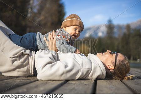 Happy Family. Young Mother Playing With Her Baby Boy Infant Oudoors On Sunny Autumn Day. Portrait Of