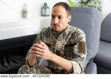 Thoughtful Military Man Staring Aside, Holding Palms By Mouth, Sitting On Couch At Home. Young Soldi