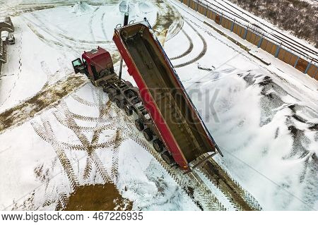 A Large Dump Truck Unloads Rubble Or Gravel At A Construction Site In Winter. Car Tonar For Transpor