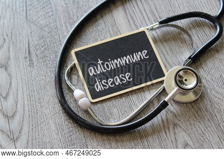 Stethoscope And Chalkboard With Text Autoimmune Disease On Wooden Table. Medical And Healthcare Conc