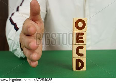 Business Concept. On A Green Surface, Cubes With The Inscription - Oecd. The Man Holds Out His Hand.