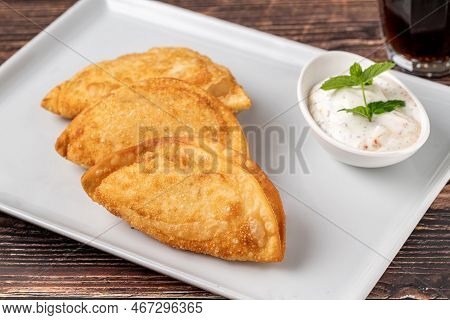Beef Cheburek On A Wooden Table. Deep Fried Beef Dumplings With Meat And Onions. Turkish Name Ci Bor