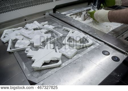 Male Worker Taking Out Models From White Polyamide Powder In Working Chamber Of 3d Printer, Cleaning