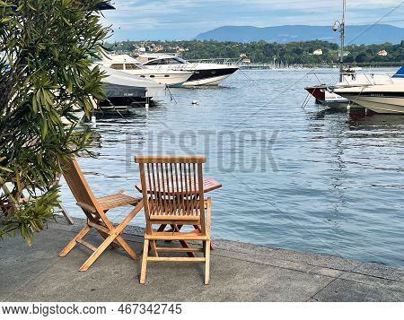 Geneva, Switzerland - September 14 2021: Two Wooden Chairs And A Table Are Placed On The Board Walk 