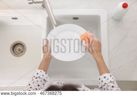 Woman Washing Plate Above Sink In Modern Kitchen, Top View
