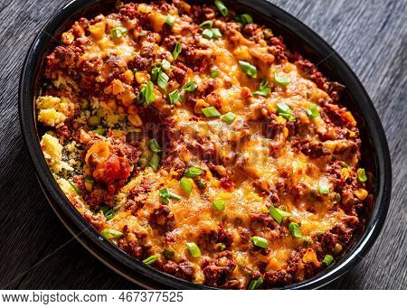 Close-up Of Cajun Beef Cornbread Casserole Topped With Melted Red Cheddar Cheese And Scalions In Bak