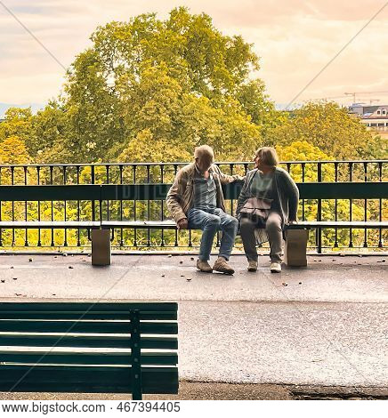 Geneva, Switzerland - September 15 2021: A Romantic View Of A Young Couple Sitting On A Park Bench I