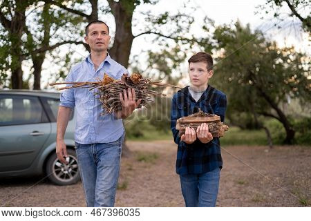 Father's Day. Son And Father In Nature. Millennial Man And Teen Boy Carrying Firewood Will Start Cam