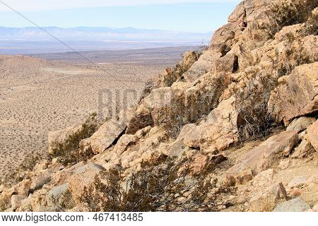 Granite Rocks And Creosote Shrubs On A Mountain Slope Overlooking The Arid Desert Plateau Taken At T