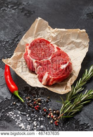 Fillet Of Raw Rib Eye Steak With Pepper,salt And Rosemary On Dark Kitchen Table Background.