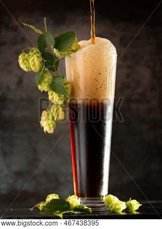 Dark Beer In A Mug And Green Hop On Wooden Table On Brown Background