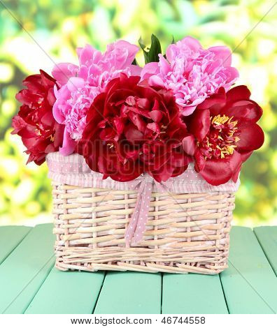 Peonies สวยงามในตะกร้าหวายในตารางบนพื้นหลังสดใส
