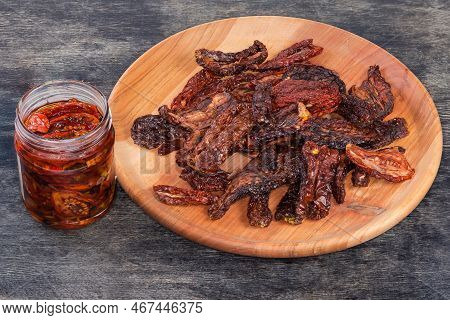 Dry-cured Red Tomatoes On The Wooden Plate And Sun-dried Tomatoes Preserved In Cooking Oil With Spic