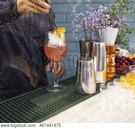 Glasses Of Cocktails On The Bar. Bartender Pours A Glass Of Sparkling Wine With Red Alcohol. Barman 