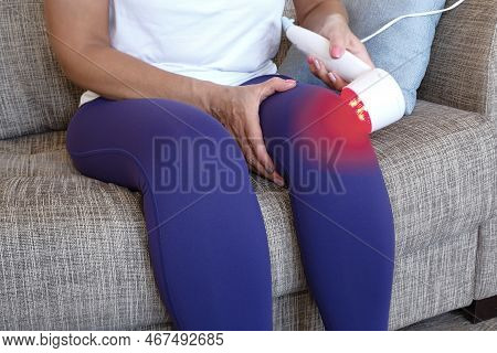 Arthritis Is A Disease Of The Joints. A Woman Applies A Uhf Therapy Device Sitting On The Couch To T