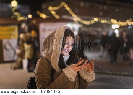 Happy Woman Using Smart Phone For Typing/reading Message While Standing On The Street. In Background