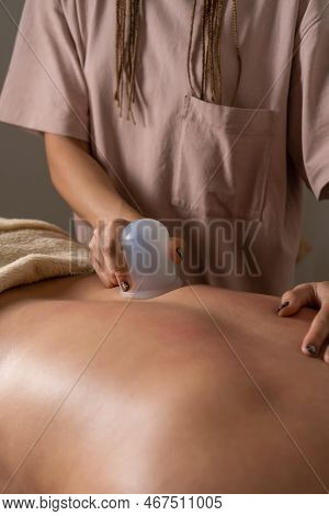 Close-up Of A Masseur Doing A Back Massage Using A Silicone Vacuum Jar. Cupping Treatment For The Tr