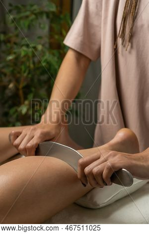 Close-up Of A Female Masseur's Hands Doing Foot Massage With A Metal Medical Massager In A Cozy Offi