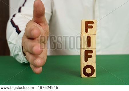 Business Concept. On A Green Surface, Cubes With The Inscription - Fifo. The Man Holds Out His Hand.