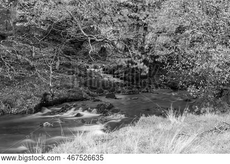 Long Exposure Of The Weir Water River Flowing Downstream Of Robbers Bridge In Exmoor National Park