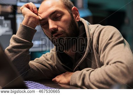 Tired Male Programmer Falling Asleep At Office Desk Working On Interface Programming, Holding Head W