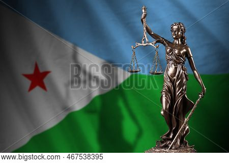 Djibouti Flag With Statue Of Lady Justice And Judicial Scales In Dark Room. Concept Of Judgement And