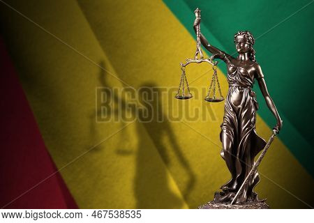 Guinea Flag With Statue Of Lady Justice And Judicial Scales In Dark Room. Concept Of Judgement And P