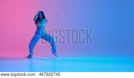 Young Stylish Girl Dancing Over Gradient Pink Blue Background In Neon Light. Hip-hop Dancer
