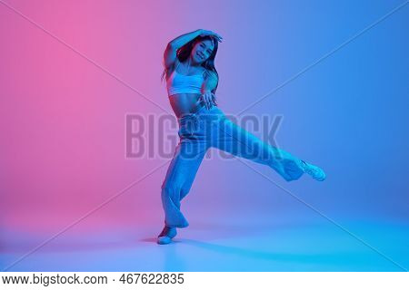 Young Active Girl Dancing Hip-hopin Sport Clothes Over Gradient Pink Blue Background In Neon Light