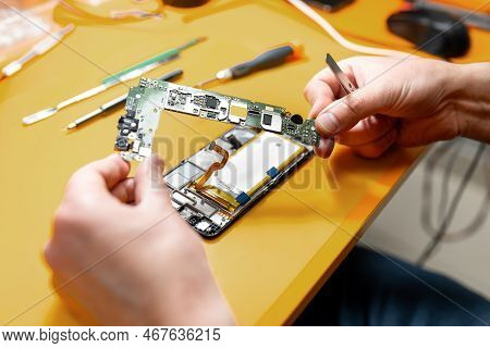 Smartphone Repair In A Service Center. Hands Of A Professional Master Repairman Repairing Disassembl