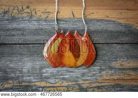 Close Up Pendant With Orange Lacquered Leaves Concept Photo. Handmade Jewelry. Top View Photography 
