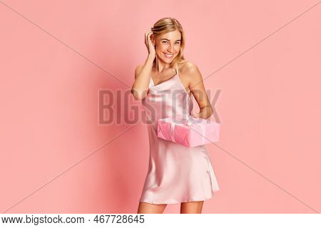 Portrait Of Beautiful Young Woman Posing In Teder Silk Dress Over Pink Background. Receiving Present