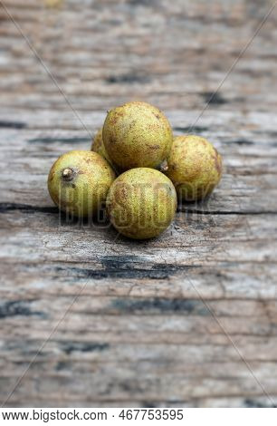 Closeup Of Schleichera Oleosa Or Kusum Fruit Isolated On Wooden Background