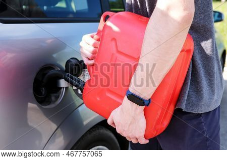 A Red Canister On The Asphalt Near The Car. The Car Ran Out Of Gas And Stalled. A Young Man Hoping F