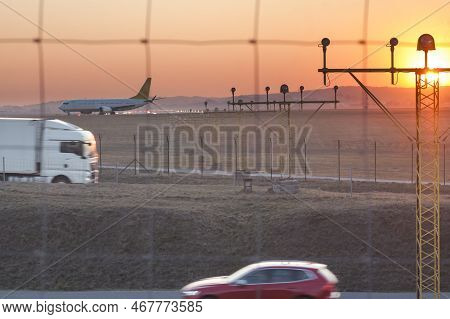 Poland, Krakow, Balice Airport, Runway Lights Andcommercial Aircraft Taxiing At Sunset,